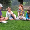 enfants assis en rond qui écoutent leur chef